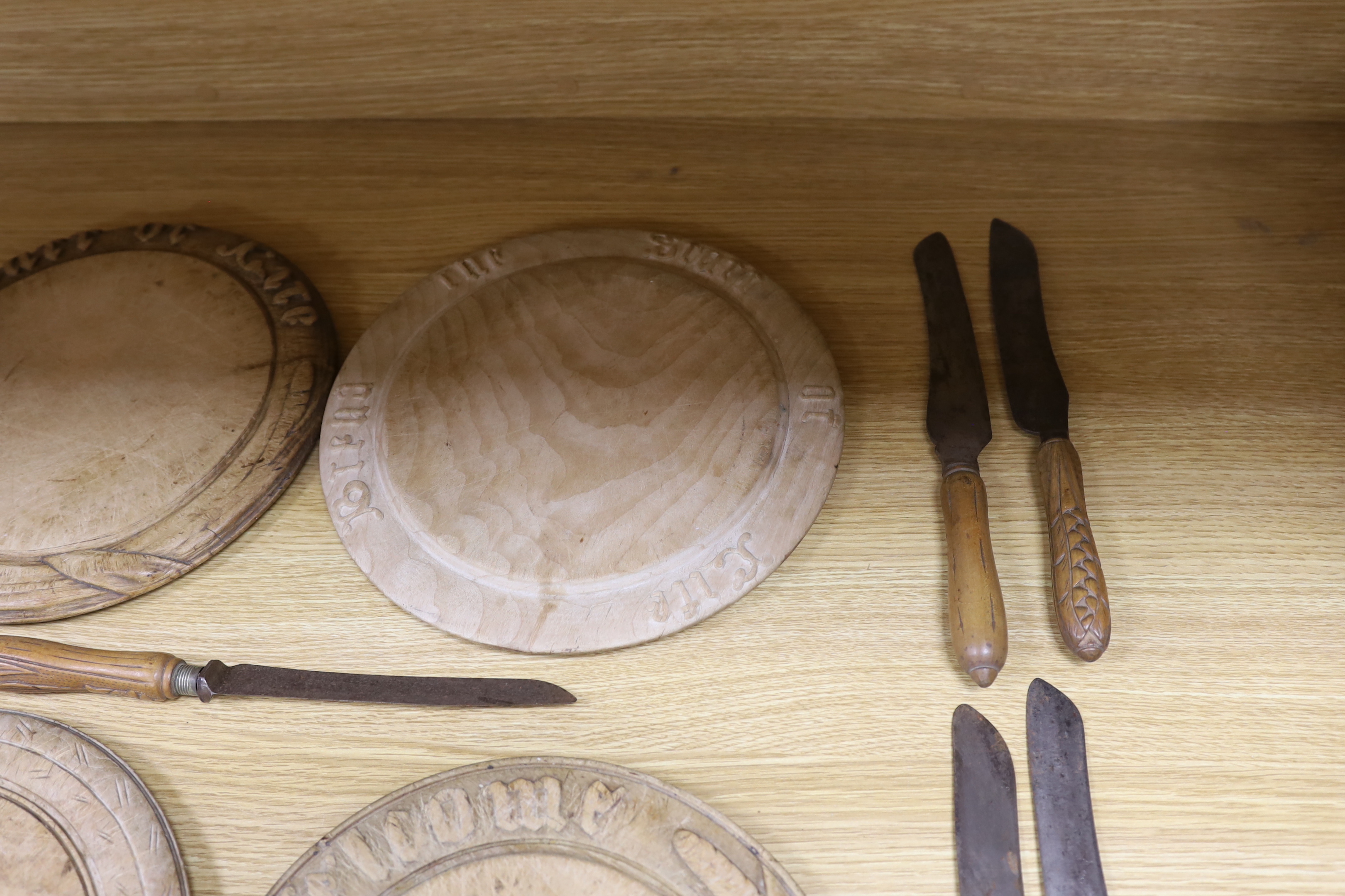 Four carved wood bread boards and a collection of knives with carved handles, boards 28cm in diameter